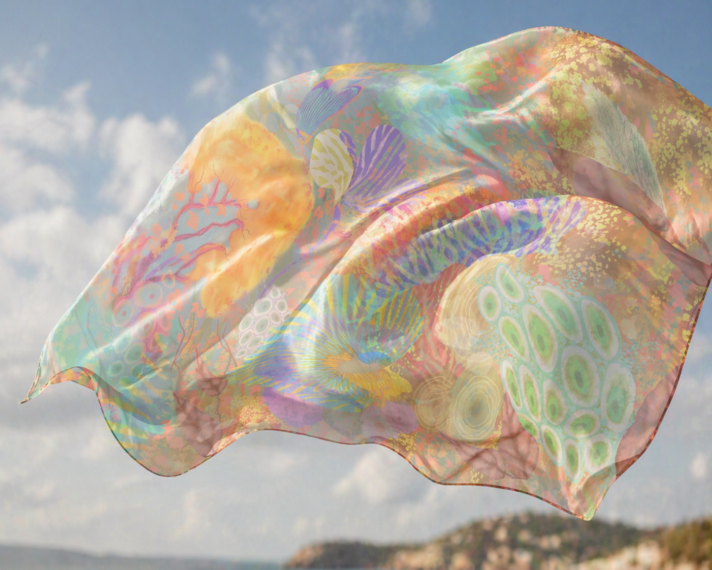 Colorful fabric with abstract patterns flowing in the wind against a sky and mountain background