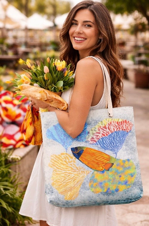 Woman holding a tote bag with a colorful coral design and flowers.