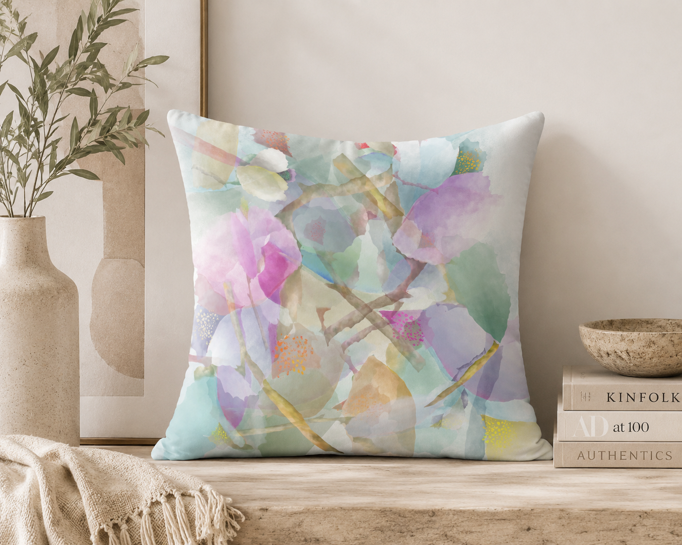 Decorative pillow with a colorful abstract design on a shelf with books and a plant.