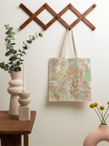 Tote bag with floral pattern hanging on a wooden hook against a light wall.